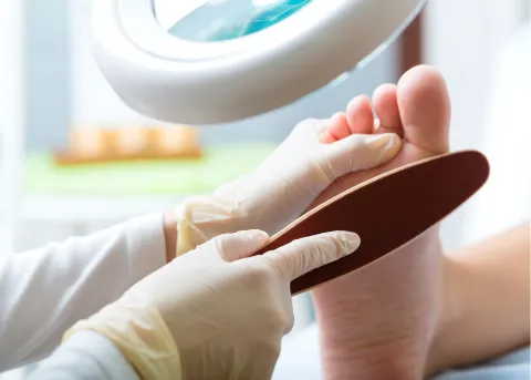foot care nurse using a callus paddle to remove dead skin from feet